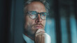 © Atchariya63 - Pensive man business leader thoughtful gaze office window natural light eyeglasses stubble beard blue eyes executive contemplation with calm focus