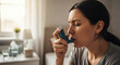 © Ksenia Pestereva - Woman using inhaler for bronchitis relief, respiratory care at home for better health. Bronchitis often requires immediate action, so this image captures a woman using her inhaler,