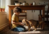 Young boy gently kneels to feed his tabby cat from a bowl in a sunlit home setting