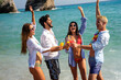 © NDABCREATIVITY - Happy friends partying at the beach with cold drinks. Carefree summer celebration by the sea