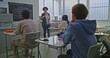 © Framestock - Female Teacher Stands Near Blackboard Explaining Coding Assignment to Group of Students in Bright Classroom. Concept of Modern Education, Interactive Learning, Creative Teamwork In School Environment.