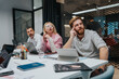 © qunica.com - Diverse professionals in a bright office collaborate over laptops and notes during a strategic meeting.