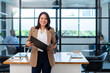 © PINA - portrait of asian businesswoman in formal suit standing at coworking space in green office, group of multiracial team colleague diverse employee coworker meeting at environment sustainable workplace