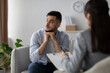© Prostock-studio - A stressed arab man sits on a couch in a clinic, deep in thought while consulting with a psychologist. He looks aside, reflecting on his feelings during the session.