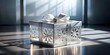 © VisualVault - Elegant white gift box with intricate snowflake design, adorned with a satin ribbon and a sparkling jewel, sits bathed in sunlight on a reflective surface.