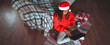 © Prostock-studio - A woman in a red sweater and Santa hat sits comfortably on the floor, using a laptop surrounded by holiday gifts. A warm blanket and mug complete the festive atmosphere.