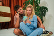 © Jose Calsina - A cheerful young couple engages in online shopping together, using a smartphone and credit card, highlighting their enjoyment of digital purchasing and shared moments in a cozy atmosphere.
