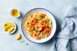 © annapustynnikova - Delicious shrimp pasta dish with lemon accents and fresh herbs. Light blue background. Top view.