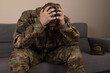 © Midea  - A man in military uniform is sitting on a couch with their head in their hands