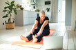 © Marko Geber - Senior woman focused on online stretching at home