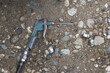 © Core - Dirty air blow gun, pneumatic tool for industrial work, lies on ground. This used equipment at workshop rests on dirt, gritty and forgotten tool