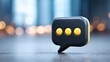 © Oulaphone - A sleek black speech bubble icon with three yellow dots, symbolizing messaging or communication, set against a blurred background.