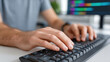 © Oatkhaphon - Programmer typing in corporate setting with focused hands on keyboard and blurred computer screen in background