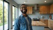 © Pete - Happy African American man smiles widely in new modern kitchen. Bright spacious room features light wood cabinets, island, large windows. Feels joy about home ownership, successful property