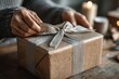 © Evhen Pylypchuk - Hands wrapping a gift with tape on textured kraft paper, soft natural light enhancing the scene, focused on the delicate details of the materials