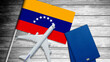 © Angelov - Flag of Venezuela with passport and toy airplane on wooden background. Flight travel concept