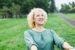 © Lumos sp - Happy active middle aged couple, portrait of a mid age woman with her husband dancing or swinging and holding hands in park outdoors