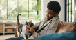 © Wess/peopleimages.com - Love, stroke and man on sofa with cat, fur rub and animal bonding on weekend break. Happy, relax and male person in house with kitten, feline best friend and pet affection on Sunday rest.