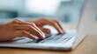 © perfectlab - A person types on a laptop keyboard with their hands in focus and the background blurred out of view