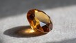© Thares2020 - A radiant faceted amber gemstone sits bathed in sunlight casting a distinct shadow on its textured surface