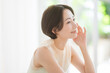 © lielos - 頬を触る笑顔のミドル世代の日本人女性。