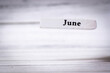 © daily_creativity - White wooden plank with the word June displayed on it. This image symbolizes the month of June, often associated with summer, warmth, and blooming flowers.