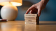 © mod - A hand placing a wooden block labeled future plan on a stack of blocks on a reflective table top