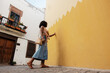 © Angel Santana - Woman touching yellow wall walking in town alley