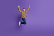 © deagreez - Young handsome guy in a checkered yellow shirt jumps with joy against a purple background for lifestyle fashion advertising