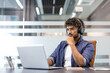 © Tetiana - Serious and focused young Indian man in headphones working in the office on a laptop