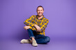 © deagreez - Young handsome man in yellow checkered shirt sits on purple studio background smiling casual lifestyle portrait