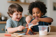 © DBA - Two young boys, a White child and a Black child, smile excitedly while pouring ingredients into a model volcano during a science experiment.