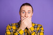 © deagreez - Young handsome guy in plaid shirt covers mouth in surprise against purple background