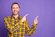 © deagreez - Young handsome guy in a yellow plaid shirt points to the right against a purple background