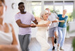 © JackF - Active mature men and women practicing Rock 'n' Roll dance in training hall during dancing classes