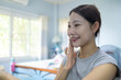 © Wuttichai Kaewklang - A woman is sitting in a chair and smiling while applying makeup