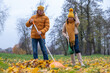 © Silga - Midlife couple raking colorful autumn leaves in a park, wearing cozy sweaters and hats, enjoying the fall season together while creating a vibrant outdoor atmosphere