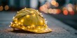 © ALL YOU NEED studio - A yellow hard hat, representing construction work, rests on a sturdy, textured surface, subtly adorned with delicate, twinkling Christmas string lights wrapped around its brim.