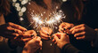 © NeuroCake - A group of friends holding burning sparklers at a night party. People celebrating a festive holiday like New Year's Eve or Christmas. Hands with fireworks against a bokeh background