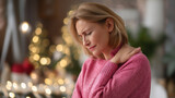 Faceless beautiful blonde woman in pink sweater suffering backache defocused indoor background touching back with hand muscular pain winter discomfort body ache seasonal pain