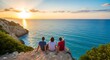 © Mouse - Three friends sitting on a cliff enjoying the beautiful ocean sunset view.