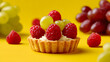 © Sunny - Mini fruit tart topped with raspberries and grapes on bright yellow background