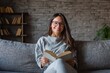 © TuruMuru - Joyful young woman reading a book on the couch