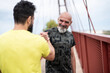 © Antonio Recena - A 65-year-old man and his 40-year-old son warm up, bumping hands to encourage each other and flexing their muscles before going for a run.