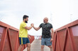© Antonio Recena - A 65-year-old man and his 40-year-old son warm up, bumping hands to encourage each other and flexing their muscles before going for a run.