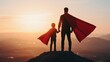 © Somkid - A silhouette of a person and child, both wearing red capes, standing on a hill against a vibrant sunset, symbolizing adventure and imagination.