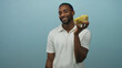 © Krakenimages.com - Young man smiling while holding a clear bowl of potato chips with hand near face in light blue studio; snacking joy.