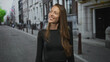 © Krakenimages.com - Woman smiling, teeth visible, looking up while wearing black long sleeve shirt on a city street lined with stone buildings; urban happiness.