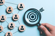 © SilentPixels - Hand holding magnifying glass focusing on target with arrow representing business goals team connections and strategic planning for success in achieving objectives and identifying key talent