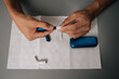 © dikushin - Top view of unrecognizable man cleaning electronic cigarette with cleaning stick and paper on table, performing maintenance, ensuring proper hygiene, sanitizing personal vaping equipment.